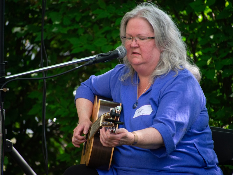 A musician plays a guitar and sings into a boom microphone